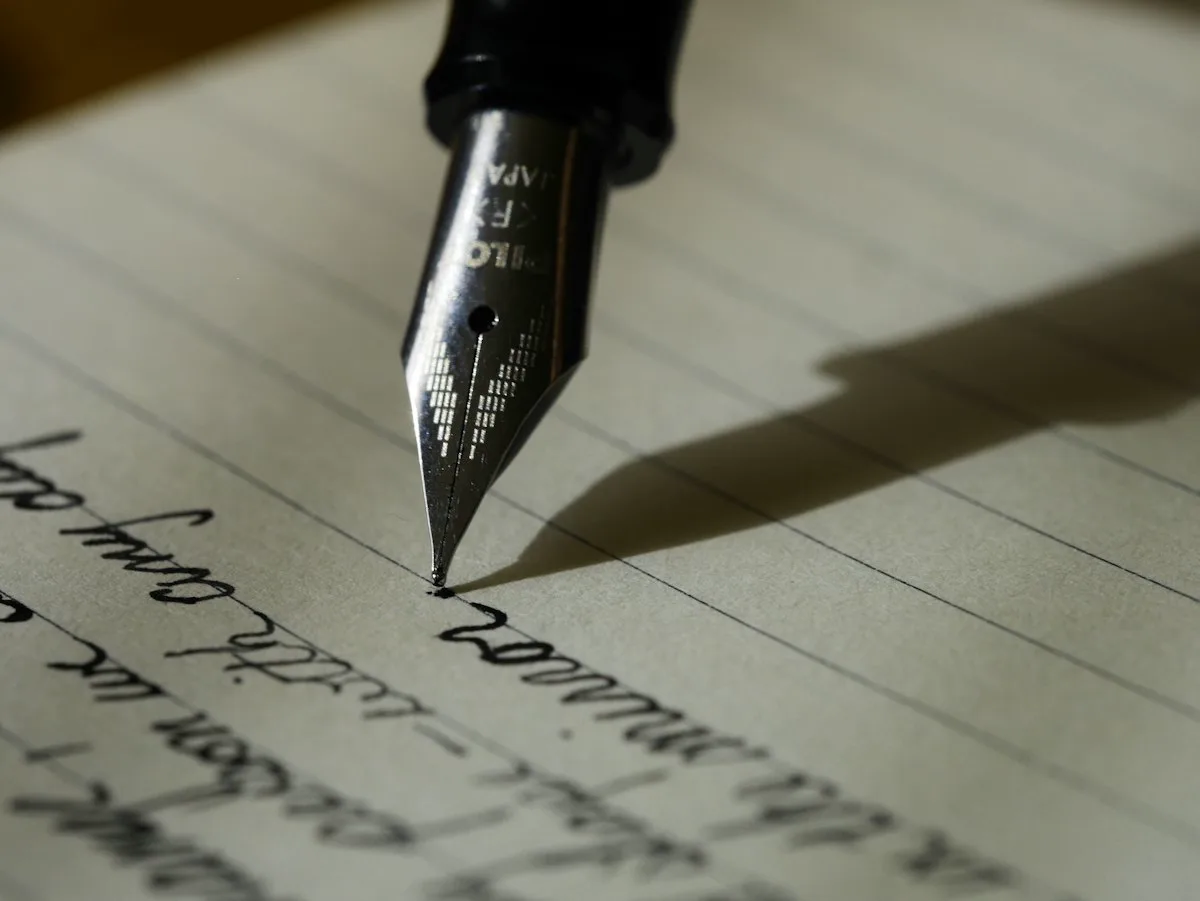 Notebook and pen on a wooden desk in warm light